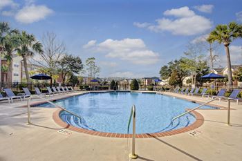 A large outdoor swimming pool surrounded by lounge chairs and umbrellas.